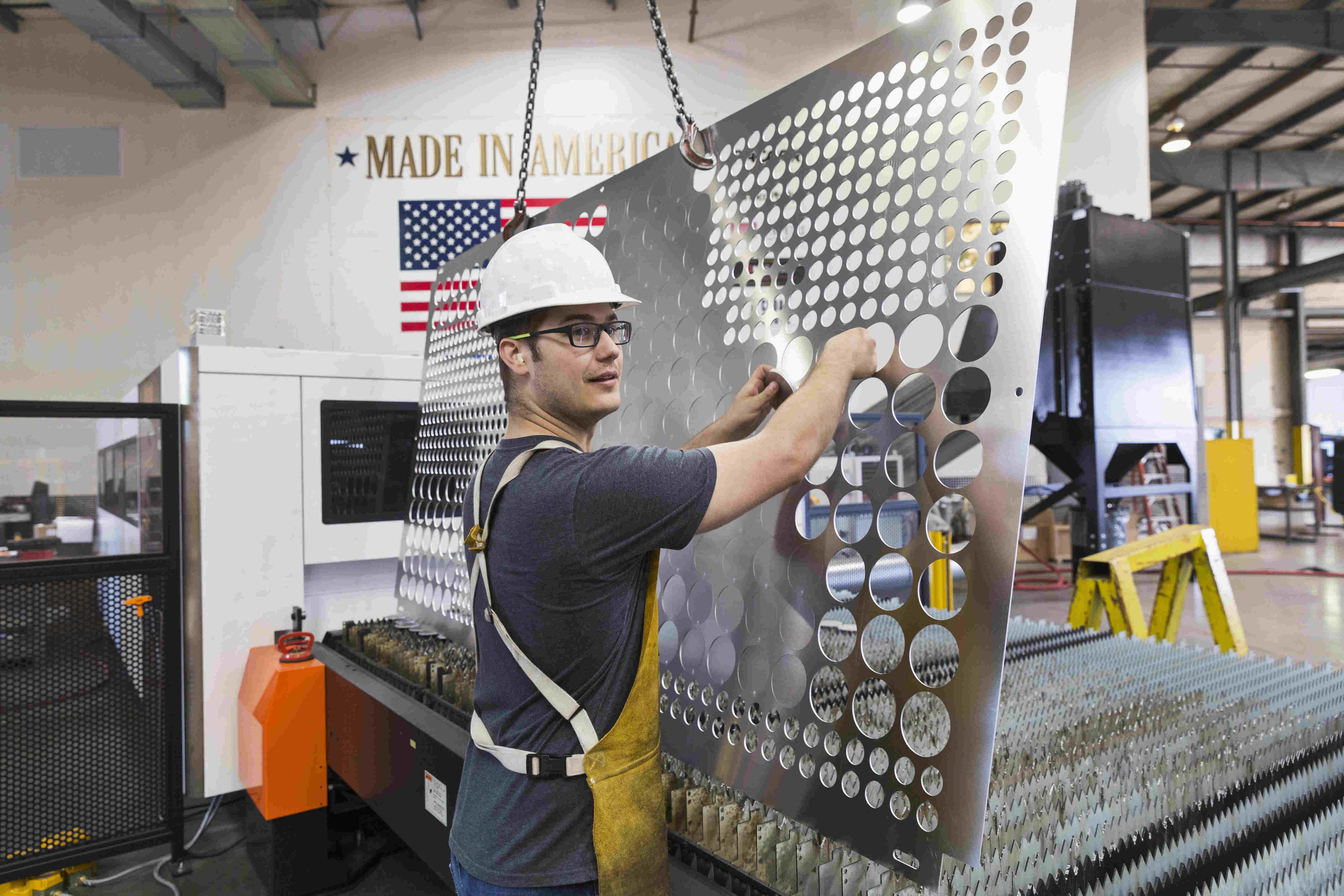 Person wearing hard hat works at a manufacturing metal cutting facility.