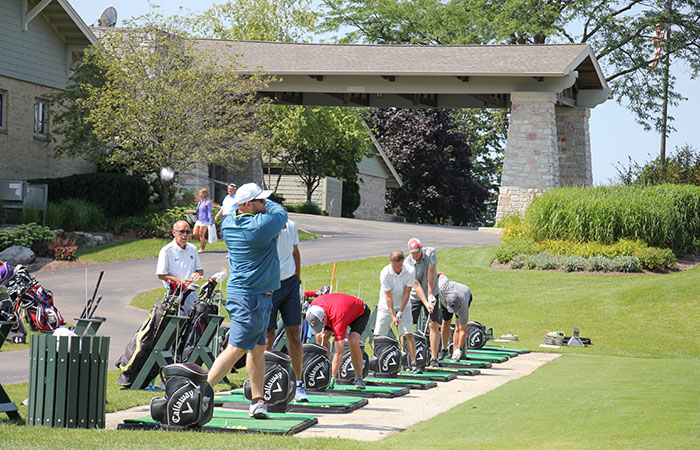 Attendees of the Silver Lining Classic practice their golf swing.