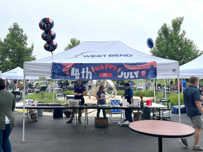 Associates serving snacks under tent on the patio at West Bend.