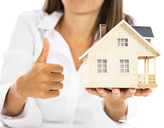 Woman gives the thumbs up sign while holding model of house