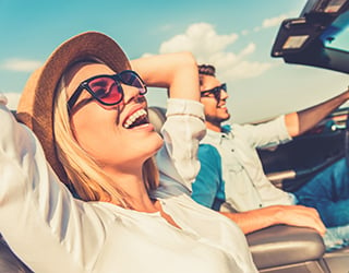 Couple drives in convertible car with roof down