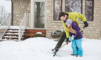 Father and daughter shoveling snow outside home