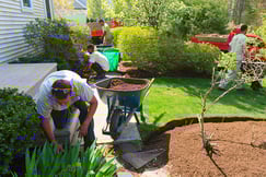 landscaping crew works on laying down mulch at house.