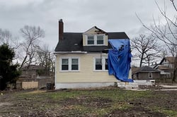 Yellow house with blue tarp hung over the right side to cover up damage from storm.