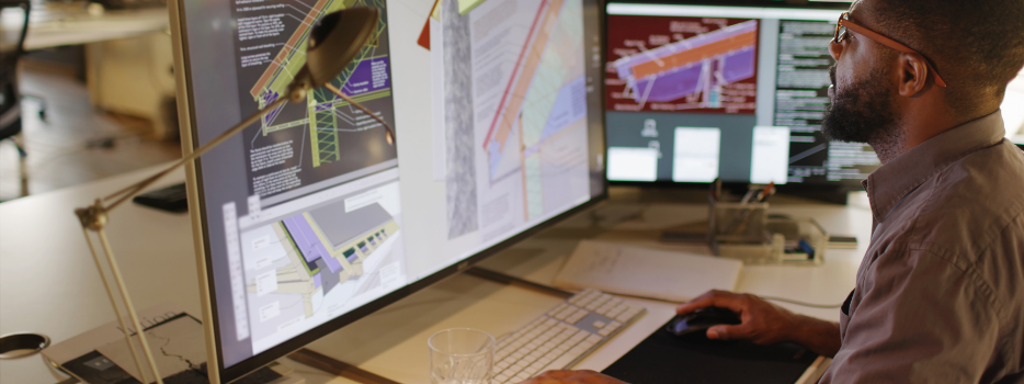 An employee looking at computers with building specs