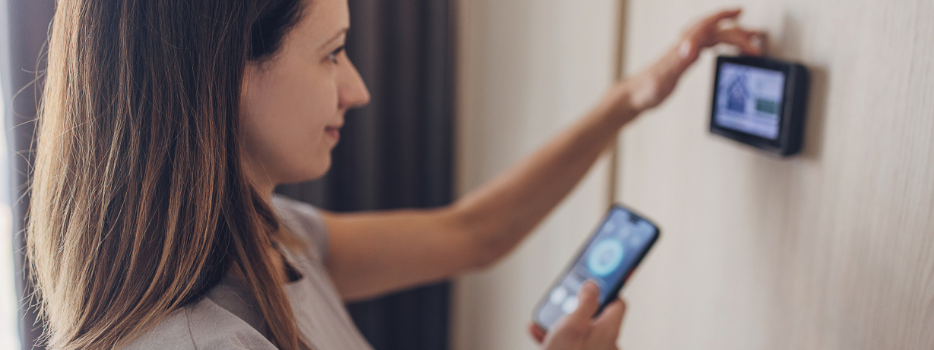 A woman checking her thermostat with her phone