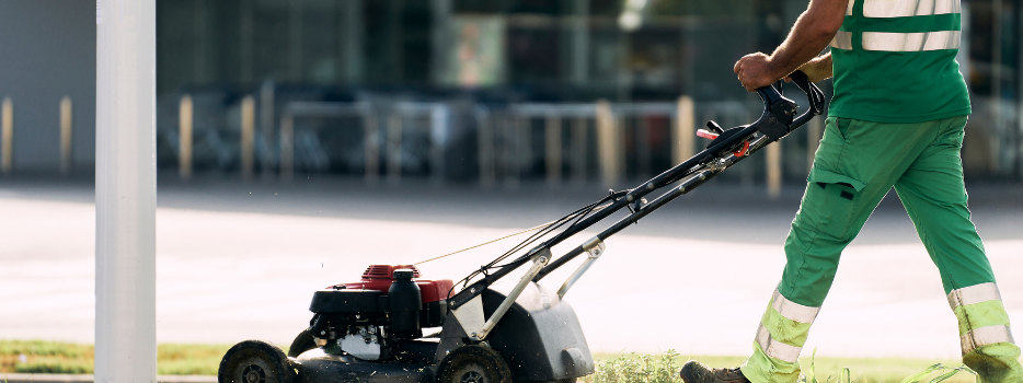 An employee mowing a sidewalk median