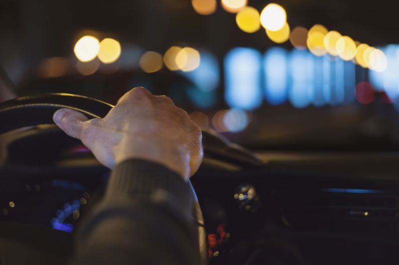 hand on a car steering wheel at night